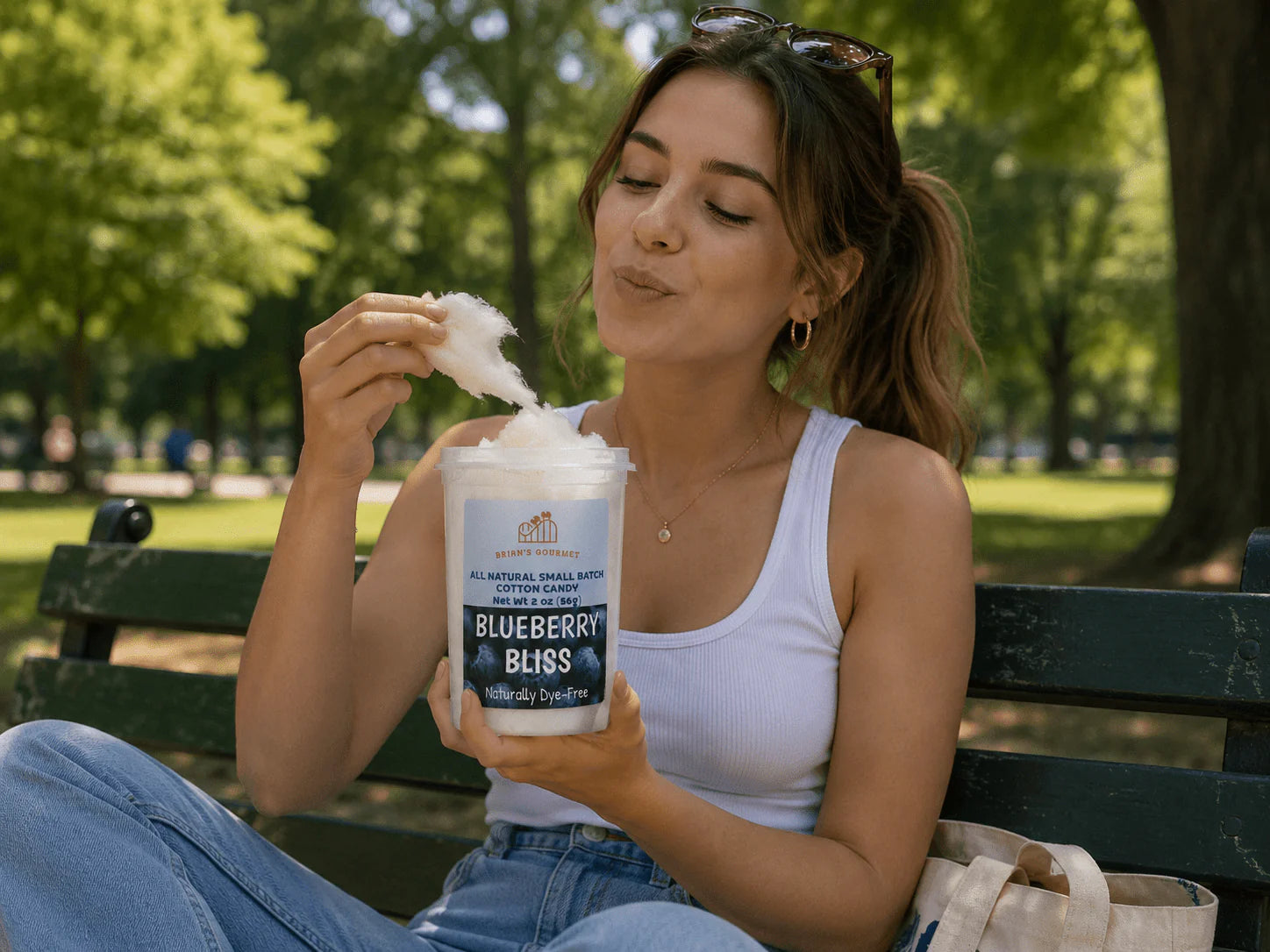Woman sitting on a bench outdoors, eating Blueberry Bliss cotton candy.